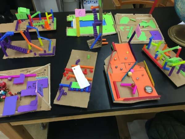 A birdseye view of 8 mini golf challenges, each on it’s own cardboard base. Each challenge includes foam pieces and straws.